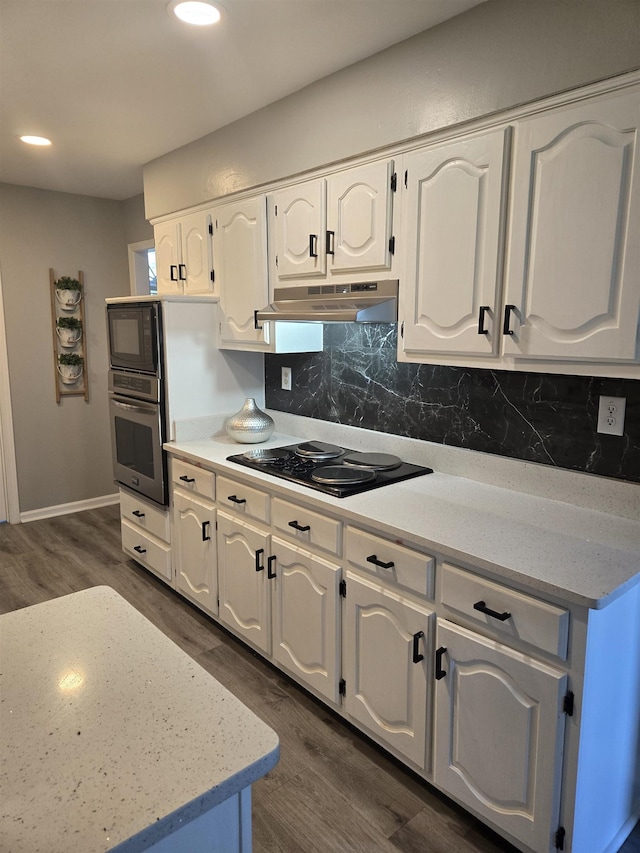 kitchen with dark wood-style flooring, black appliances, white cabinets, and under cabinet range hood
