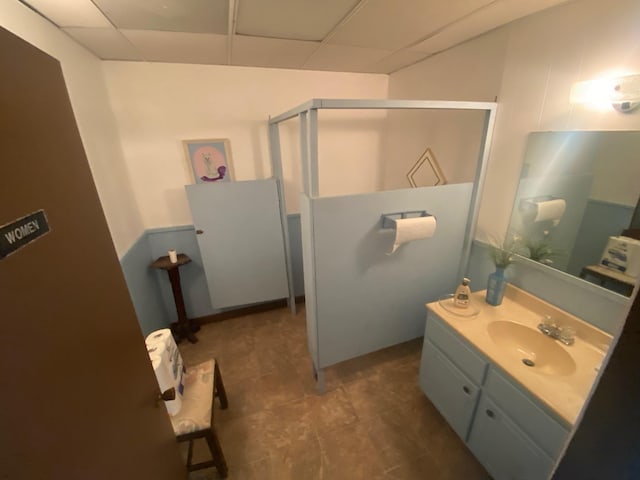 full bathroom with vanity, a shower stall, and a paneled ceiling