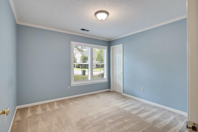 spare room featuring a textured ceiling, carpet flooring, ornamental molding, and baseboards