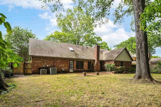 rear view of property with brick siding, a patio area, central AC, and a chimney