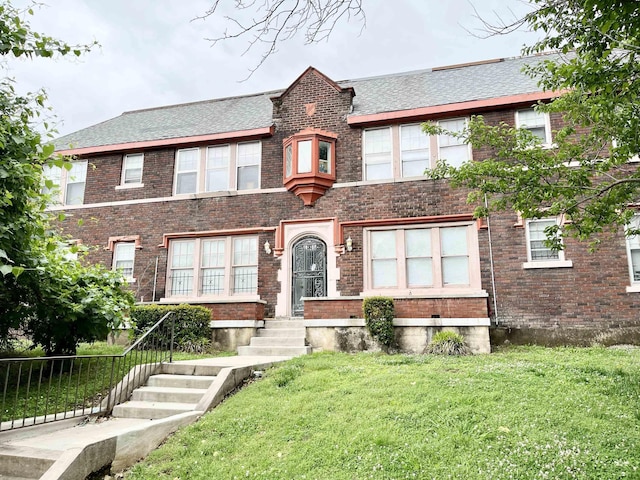 view of front of property with fence, a front lawn, and brick siding
