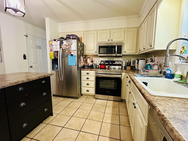 kitchen with a sink, cream cabinets, light tile patterned flooring, dark cabinets, and appliances with stainless steel finishes