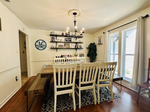 dining space featuring an inviting chandelier, wood finished floors, baseboards, and a healthy amount of sunlight