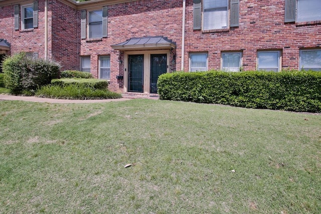 property entrance with a yard and brick siding