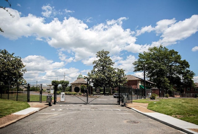 view of gate with fence and a lawn