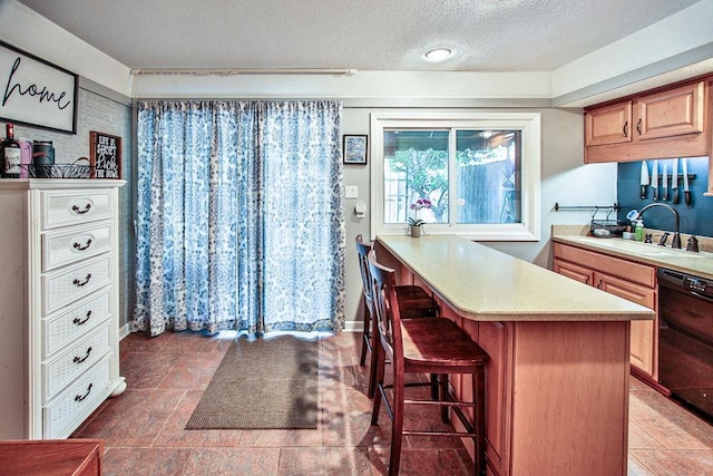 kitchen featuring a sink, a peninsula, black dishwasher, a breakfast bar, and light countertops