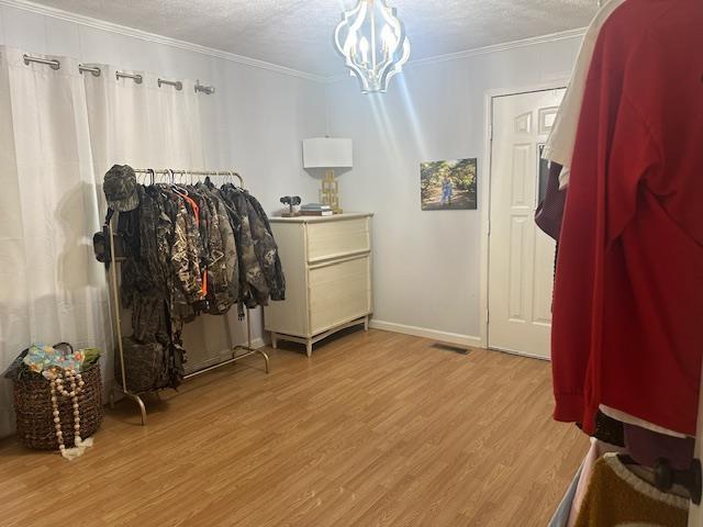 bedroom featuring crown molding, wood finished floors, baseboards, and a notable chandelier