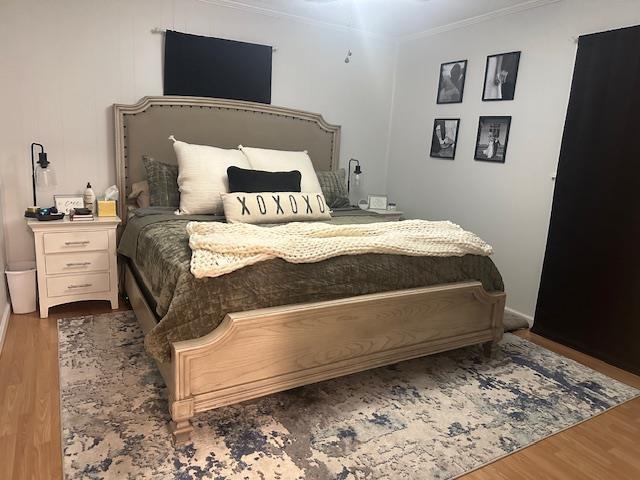 bedroom featuring crown molding, wood finished floors, and baseboards