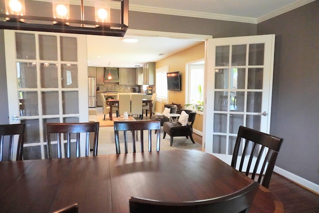 dining space with baseboards, ornamental molding, and wood finished floors
