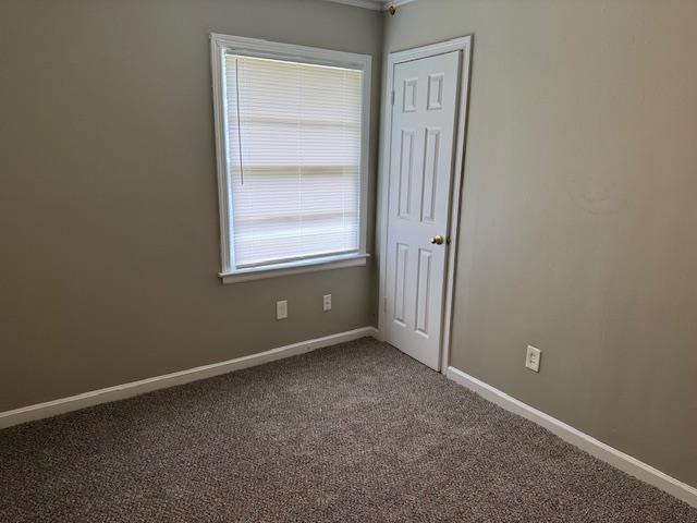 unfurnished room with carpet and baseboards