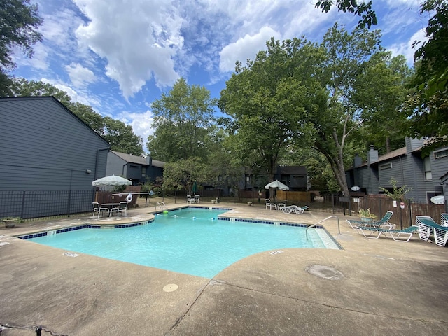 pool with a patio area and fence