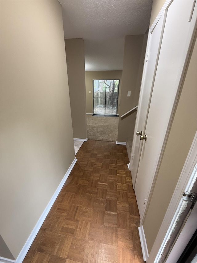 hallway featuring a textured ceiling and baseboards