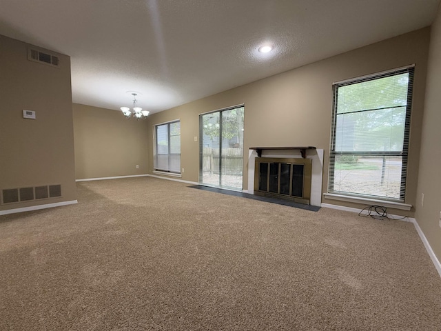 unfurnished living room with baseboards, a notable chandelier, visible vents, and a fireplace with flush hearth