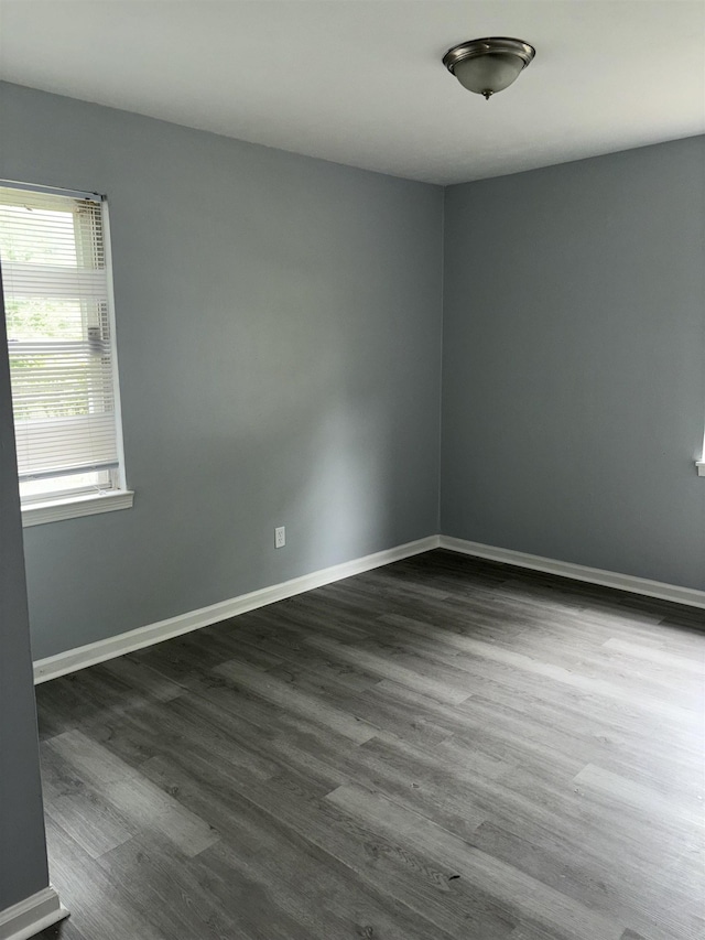unfurnished room with dark wood-type flooring and baseboards