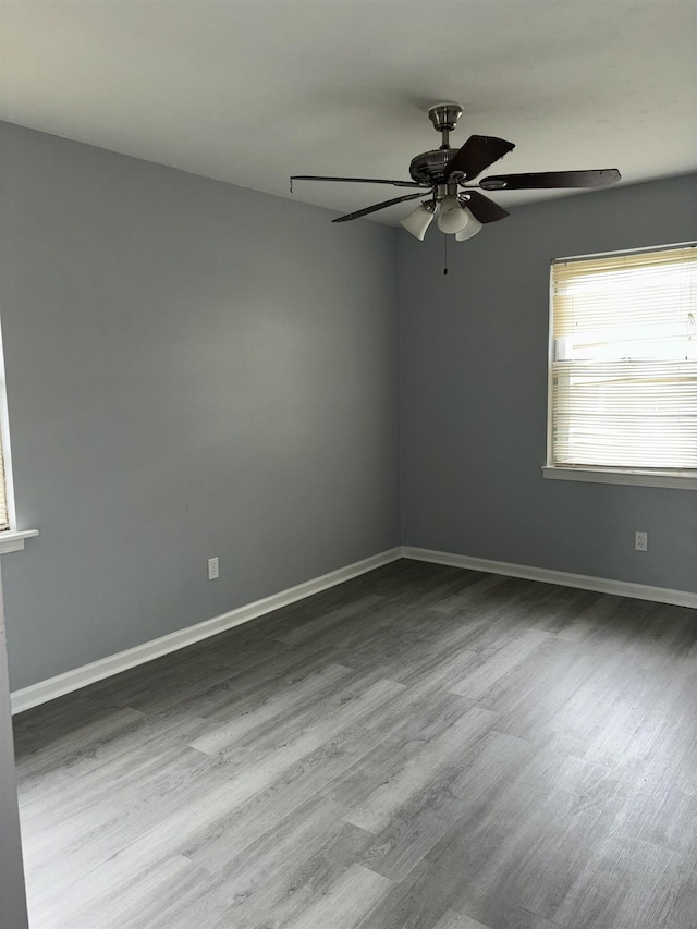 spare room with dark wood finished floors, baseboards, and ceiling fan
