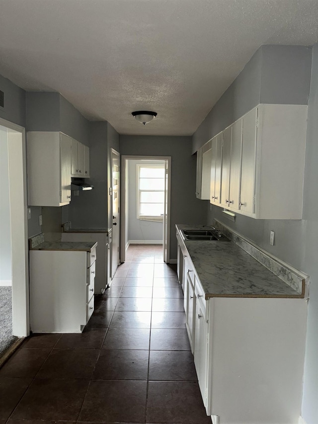 kitchen with a sink, a textured ceiling, exhaust hood, and white cabinets