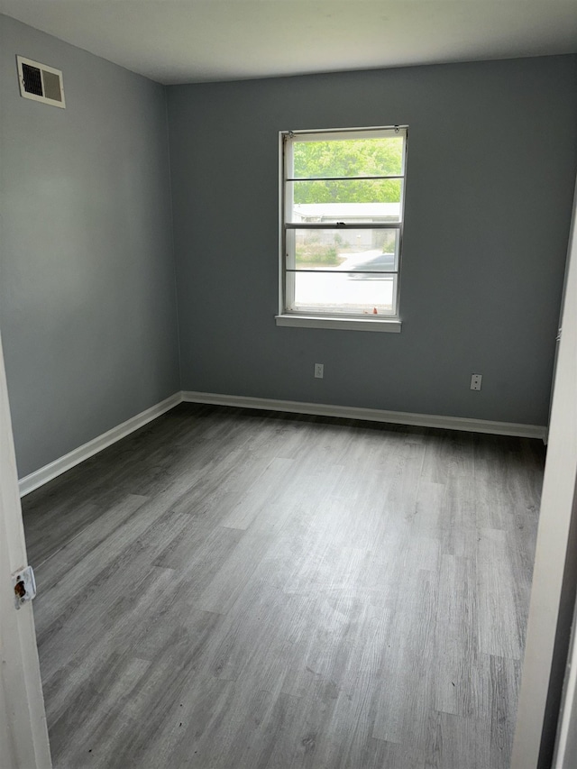 empty room with visible vents, wood finished floors, and baseboards