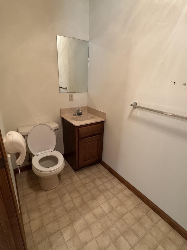 bathroom with toilet, baseboards, and vanity