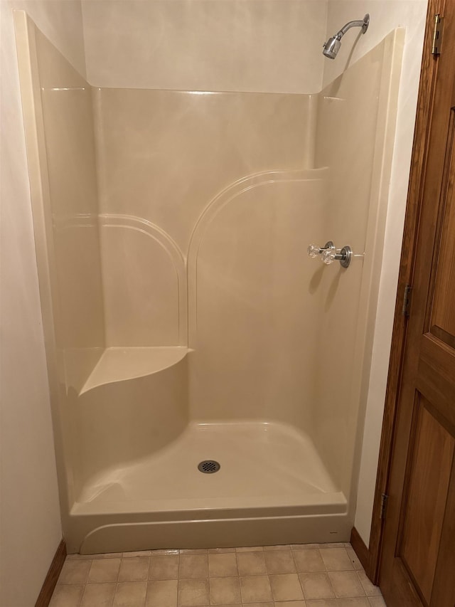 bathroom featuring walk in shower, baseboards, and tile patterned floors