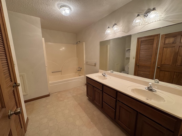 bathroom with a textured ceiling, a sink, tile patterned floors, tub / shower combination, and double vanity
