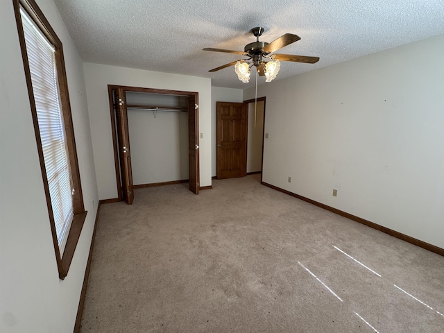 unfurnished bedroom featuring ceiling fan, light carpet, a textured ceiling, and a closet