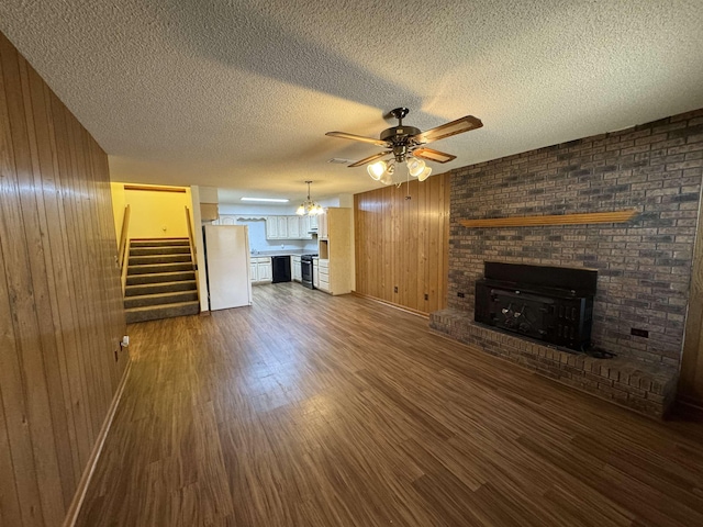 unfurnished living room with dark wood-type flooring, a fireplace, ceiling fan, and wooden walls