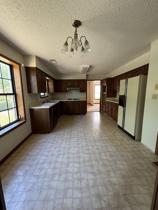 kitchen featuring an inviting chandelier, light countertops, white fridge with ice dispenser, and a healthy amount of sunlight