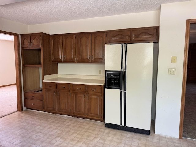 kitchen with light floors, a textured ceiling, light countertops, and white fridge with ice dispenser