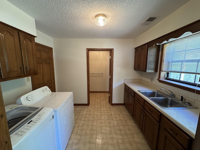 washroom featuring a sink, cabinet space, light floors, visible vents, and washing machine and clothes dryer