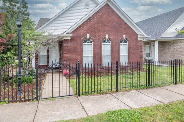 view of front of home featuring a fenced front yard, a front yard, brick siding, and a gate