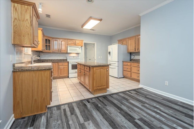 kitchen featuring light wood finished floors, glass insert cabinets, a center island, visible vents, and white appliances