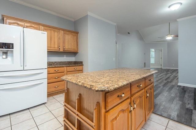 kitchen featuring lofted ceiling, light stone counters, white fridge with ice dispenser, a center island, and a ceiling fan