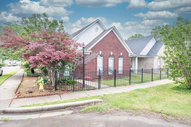 view of front facade with fence private yard, roof with shingles, brick siding, and a front yard