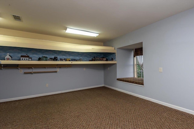 below grade area featuring baseboards, visible vents, and dark carpet