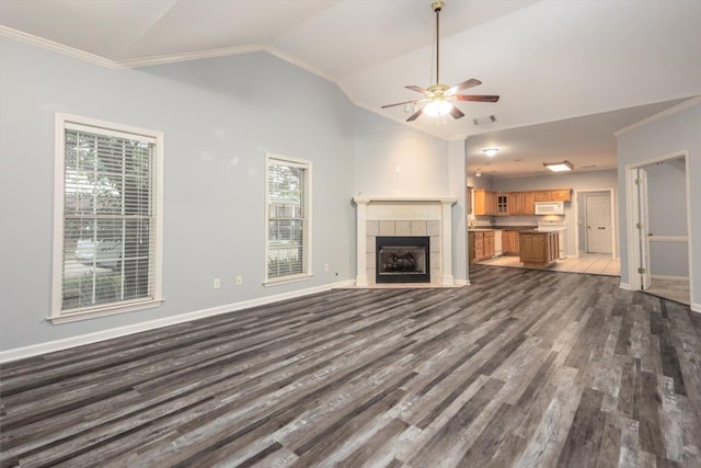 unfurnished living room with ceiling fan, dark wood finished floors, vaulted ceiling, and ornamental molding