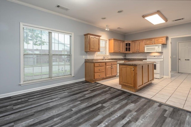 kitchen with a kitchen island, visible vents, a sink, and white appliances
