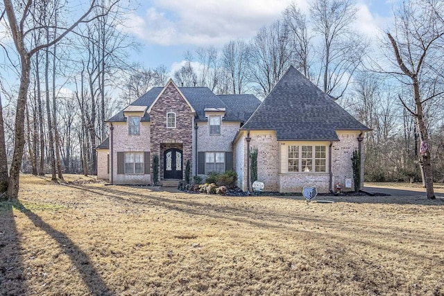 view of front facade featuring stone siding, a shingled roof, and brick siding