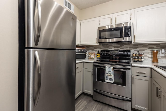 kitchen with decorative backsplash, light countertops, visible vents, and appliances with stainless steel finishes