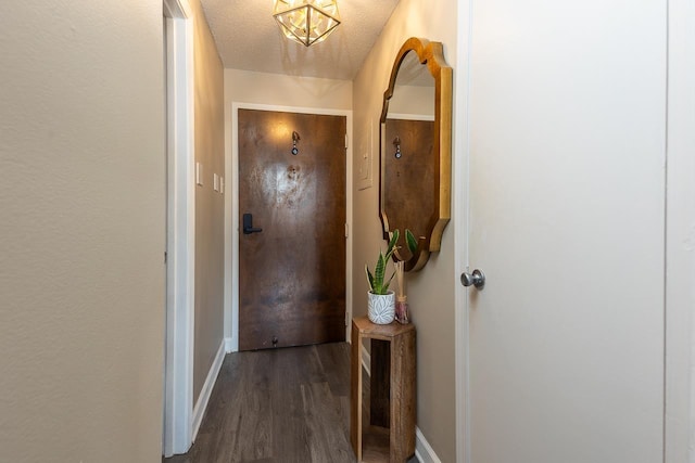doorway to outside with dark wood finished floors, baseboards, and a textured ceiling
