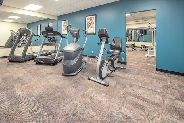 gym featuring baseboards, a drop ceiling, and carpet flooring