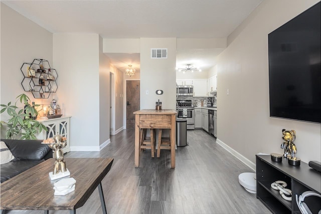 living area with baseboards, visible vents, and wood finished floors