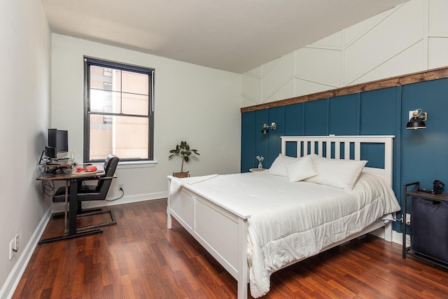 bedroom featuring baseboards, a decorative wall, and wood finished floors