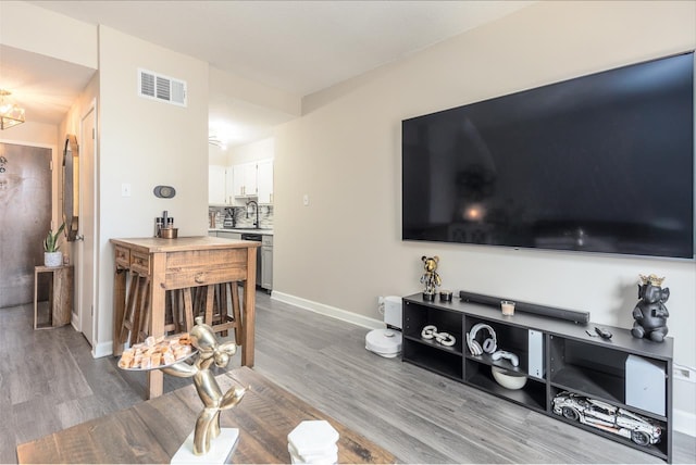 living area with baseboards, visible vents, and wood finished floors