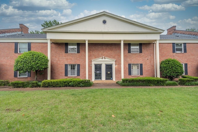 neoclassical / greek revival house with brick siding and a front lawn