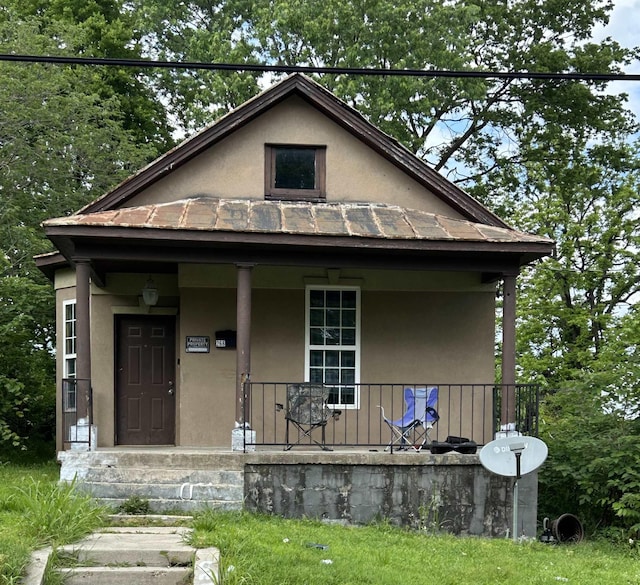 bungalow-style house with a standing seam roof, metal roof, stucco siding, and covered porch