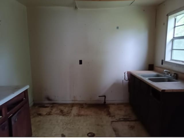 kitchen featuring baseboards, light countertops, and a sink