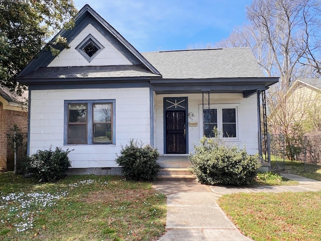 bungalow-style house with a shingled roof, a front yard, and crawl space