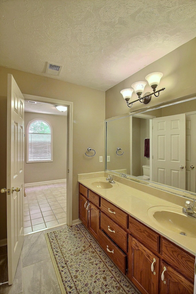 1599 John Ridge Dr, Collierville, TN 38017 - bathroom featuring double vanity, a textured ceiling, tile patterned floors, baseboards, and a chandelier