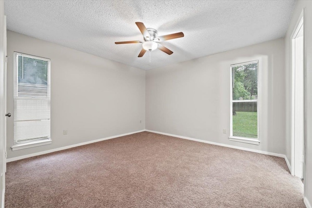 carpeted empty room featuring ceiling fan, a textured ceiling, and baseboards