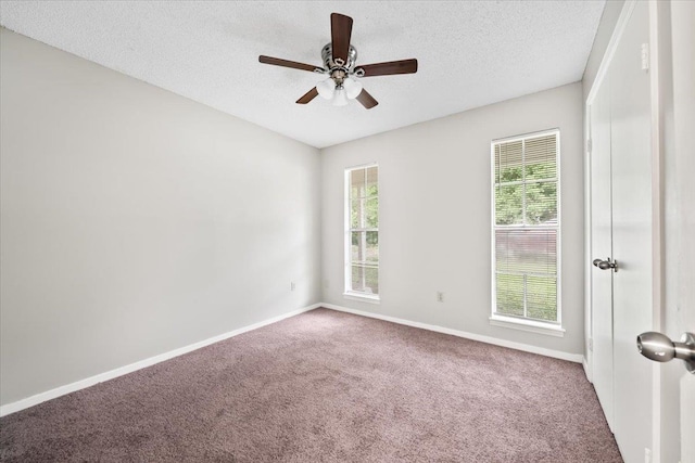 unfurnished room with carpet flooring, plenty of natural light, a textured ceiling, and a ceiling fan